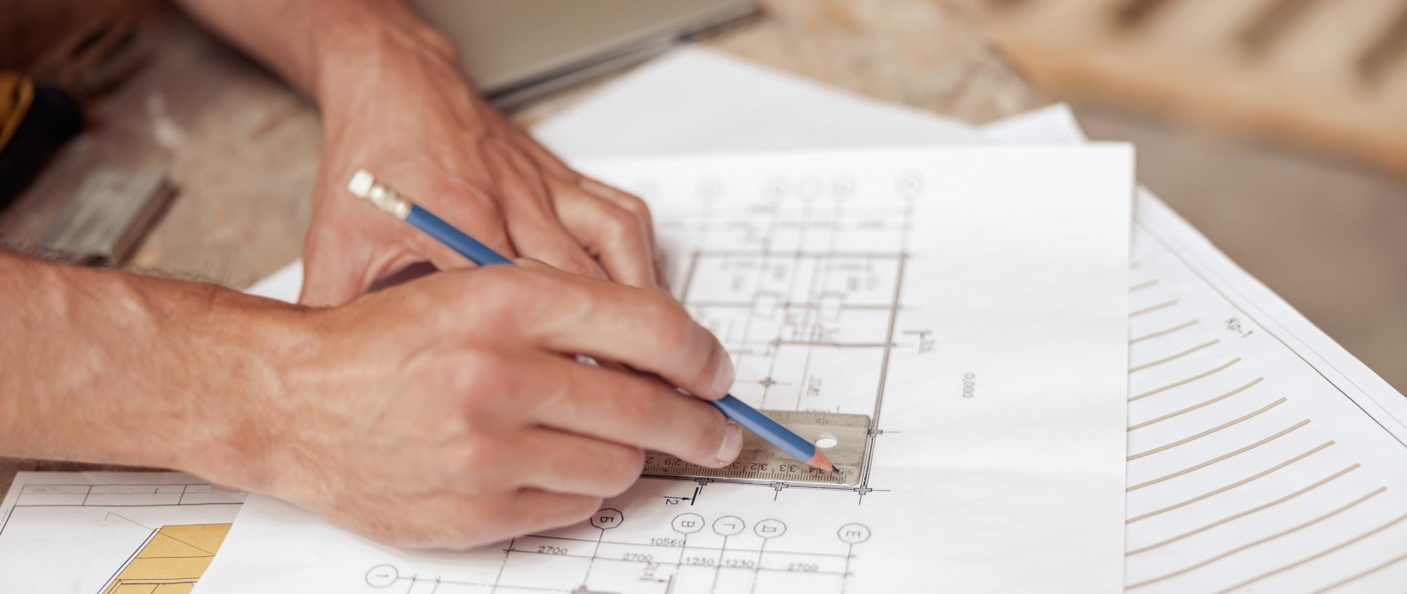 Man using ruler and pencil while working on home drawings.